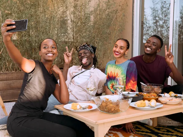 Four friends pull faces for a group selfie over a shared meal