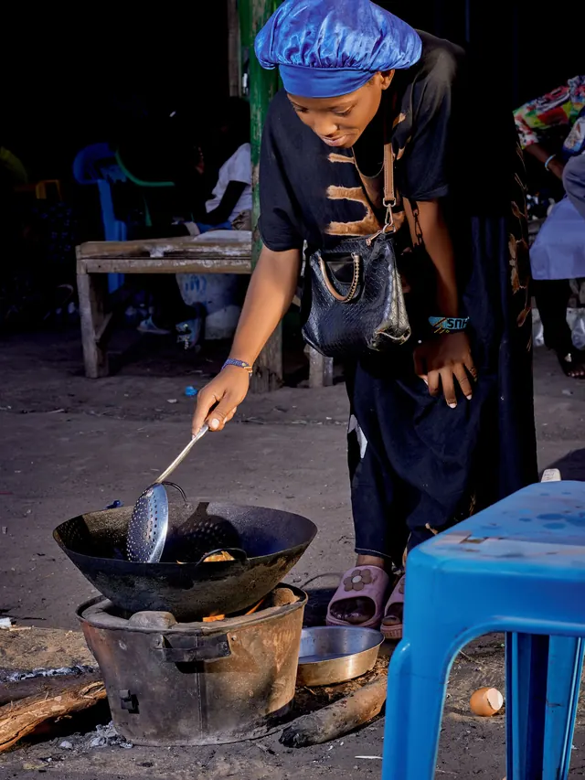 A cook fries in a wok over a charcoal jiko at a night market