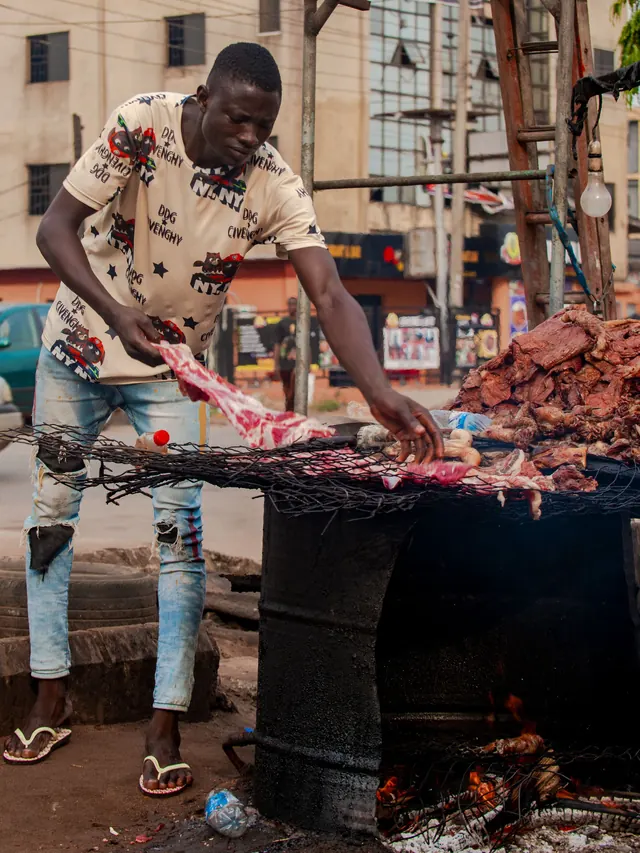 A young man grills meat on a roadside drum grill
